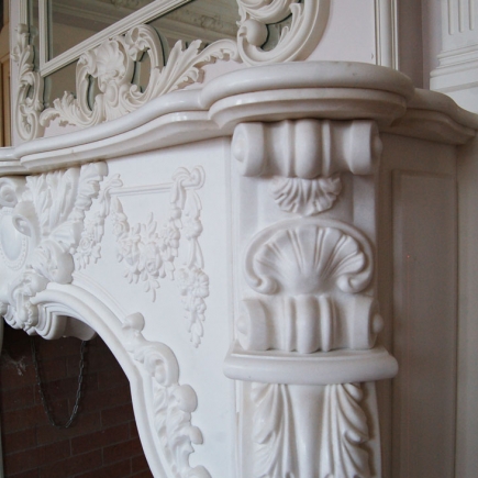 Close-up of the hand-carved marble fireplace mantel with scrollwork and shell motifs