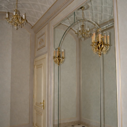 Corner detail of the mirrored hallway with a crystal chandelier reflection and paneled door