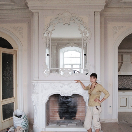 Homeowner beside the finished carved marble fireplace and ornate overmantel mirror