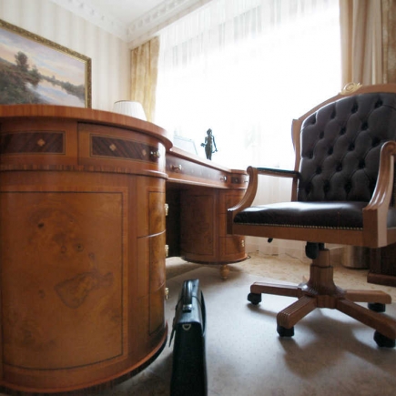 Classic burl-wood desk with a tufted leather executive chair by the window