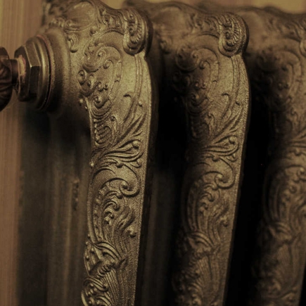 Close-up of an ornate cast-iron radiator with scrollwork detailing