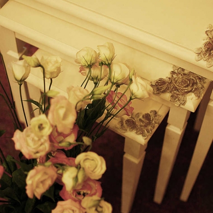 Close-up of fresh roses and lisianthus arranged beside a carved console table