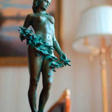 Close-up of the bronze nymph statue beside a warm floor lamp