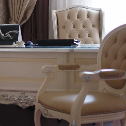 Close-up of the cream desk with tufted leather chairs and a black portfolio