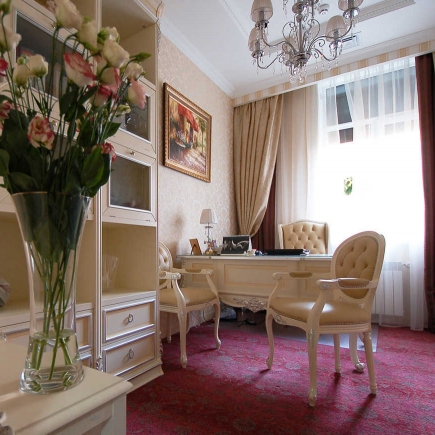 Cream office with a crystal chandelier, fresh flowers, and a burgundy carpet
