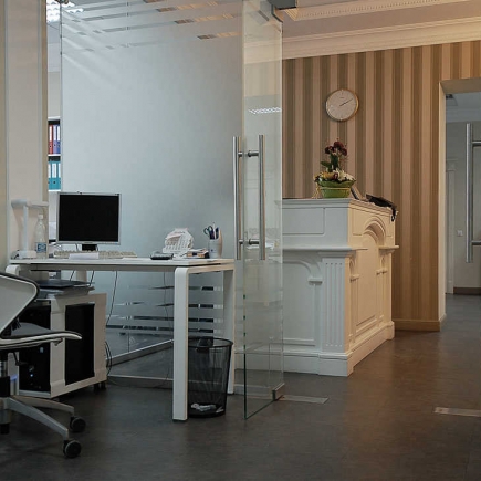 Glass-partitioned workstation beside the reception desk with striped wallpaper