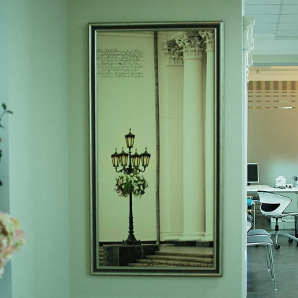 Mirror reflecting a lamppost and columns, with an office workstation visible through the doorway