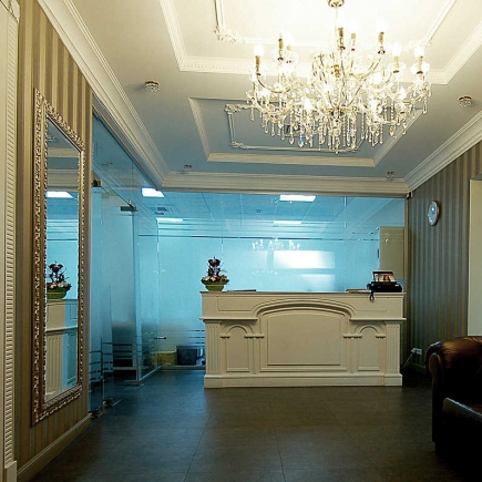 Reception hall with a crystal chandelier, gilt mirror, and illuminated glass wall partitions