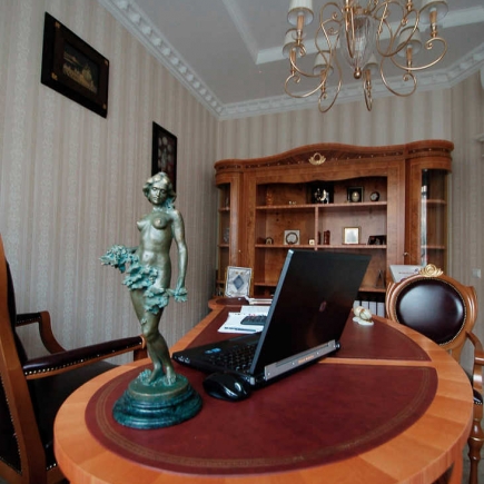 Wide view of the director's office with the bronze statue, laptop, and glass-front bookcase