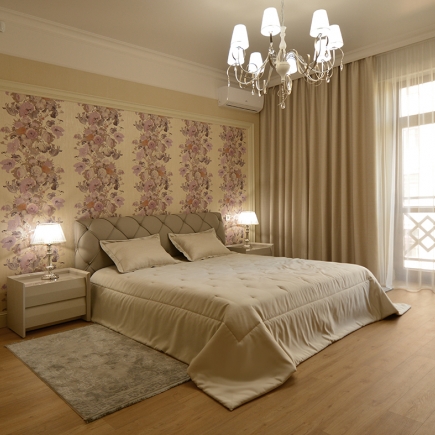 Bedroom with a floral wallpaper accent wall, tufted headboard, and crystal chandelier
