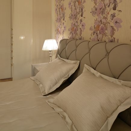 Close-up of the tufted headboard and pillows against floral wallpaper