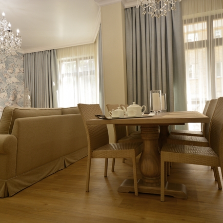 Dining nook with a woven-chair table set against sheer curtains and flamingo-print wallpaper