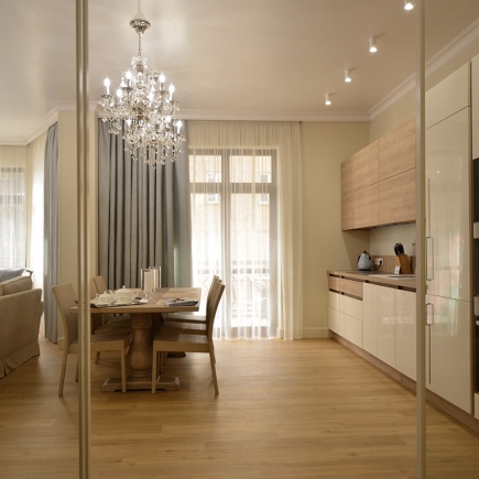 Dining table and crystal chandelier framed by the glass sliding partition, kitchen beyond