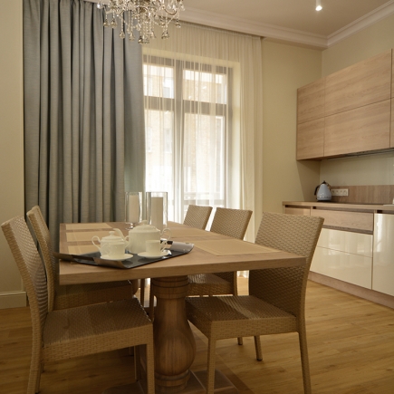 Dining table set for tea beside sheer curtains and the light oak kitchen