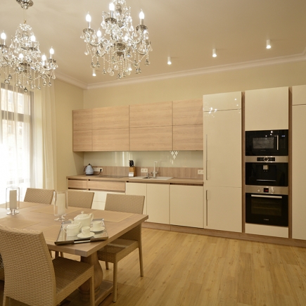 Kitchen and dining area with crystal chandeliers, light oak cabinetry, and woven dining chairs