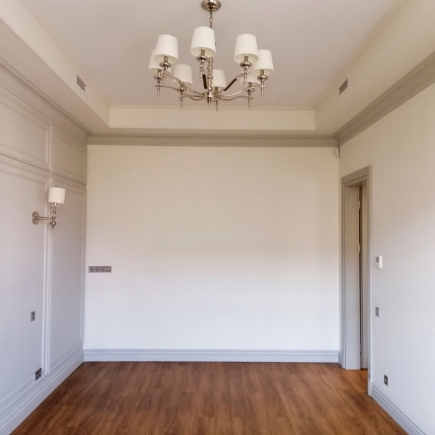 Bright reception hall with a crystal chandelier seen through open lattice-glass double doors