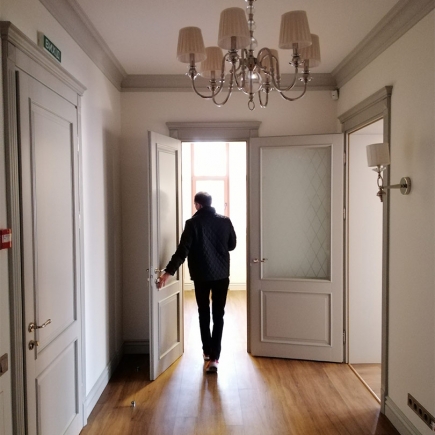 Corridor detail with a climate-control panel and twin sconces beside a grey lattice-glass door