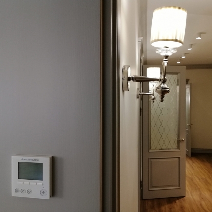 Crystal chandelier above hardwood floors with a glimpse of the office kitchen doorway