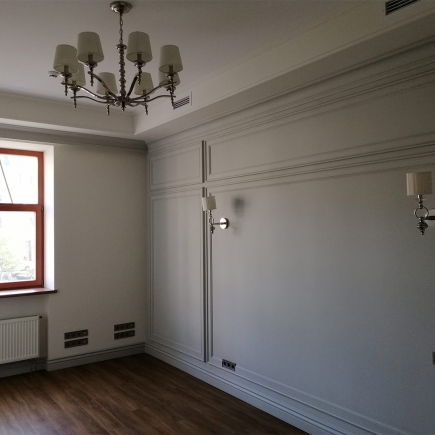 Empty office room with classical panelling, wall sconces and a red-framed window