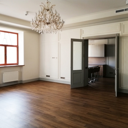 Office kitchen with a tall grey fridge and a breakfast bar with brown leather stools