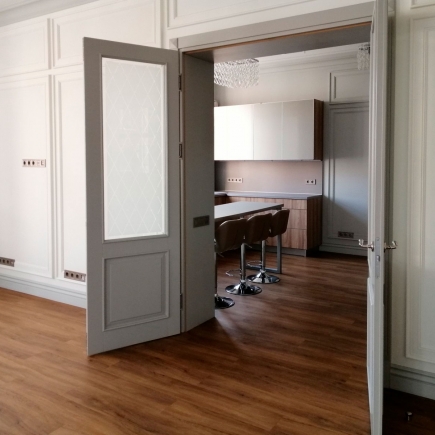 Powder room with ornate relief panelling glimpsed past an open panel door