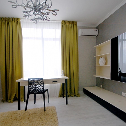 Home office nook with a black desk and chair, mustard-yellow curtains, and a sculptural chandelier