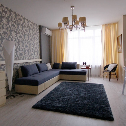 Living room with damask-print accent wall, gray sectional sofa, and layered curtains