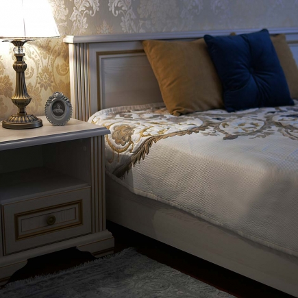Bedside table with a vintage lamp and framed portrait beside the upholstered headboard