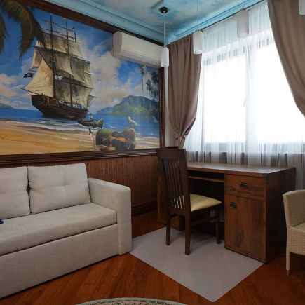 Child's room desk and sofa beneath a hand-painted pirate ship mural