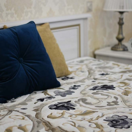Close-up of navy velvet pillows on a floral quilted bedspread
