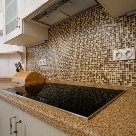 Close-up of the granite countertop with mosaic tile backsplash and an induction cooktop