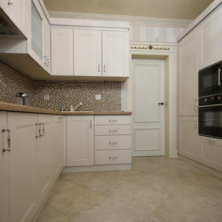 Cream kitchen with mosaic tile backsplash, built-in oven and microwave, and a mint-green door