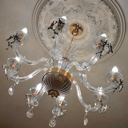 Crystal chandelier with wrought-iron branch details beneath an ornate ceiling medallion