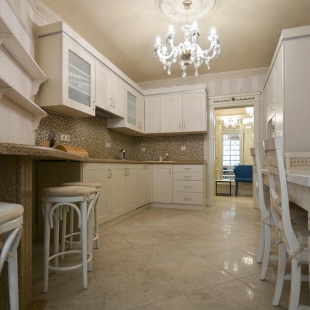 Kitchen with cream cabinetry, marble countertops, mosaic tile backsplash, and a crystal chandelier