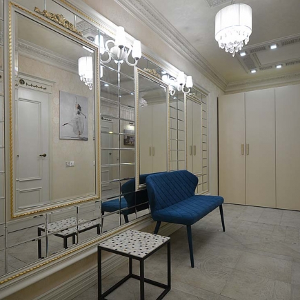 Mirrored hallway with built-in wardrobes, a navy bench, and crystal wall sconces