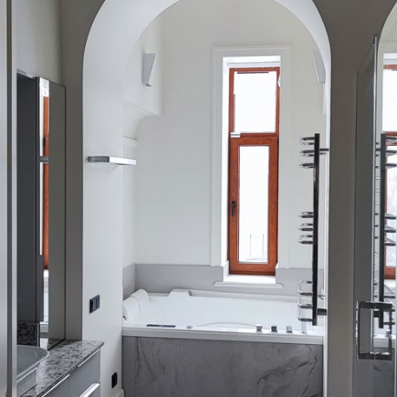 Arched doorway framing a soaking tub beneath a wood-framed window