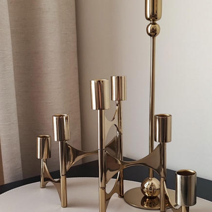 Brass candelabra set on a side table beside linen drapery