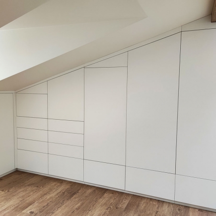 Built-in wardrobe cabinetry following the slope of an attic ceiling