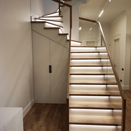 Curved staircase beside built-in storage closet with wood flooring