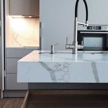 Floating marble countertop detail beside a built-in oven and marble backsplash