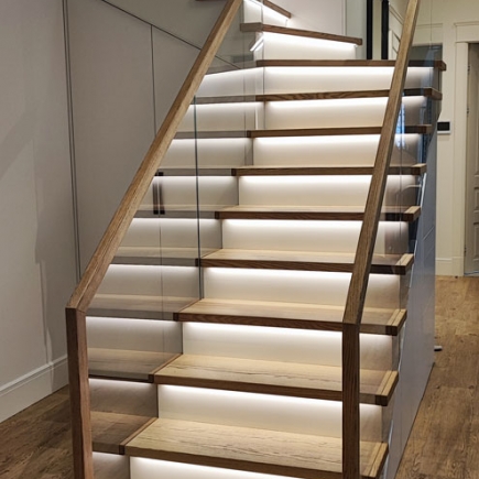 Floating wood staircase with backlit LED step lighting and glass railing