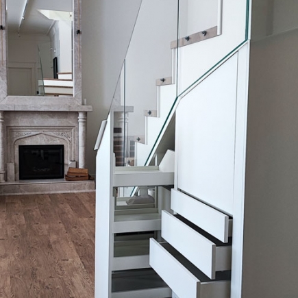 Glass-railed staircase beside a marble fireplace with carved surround