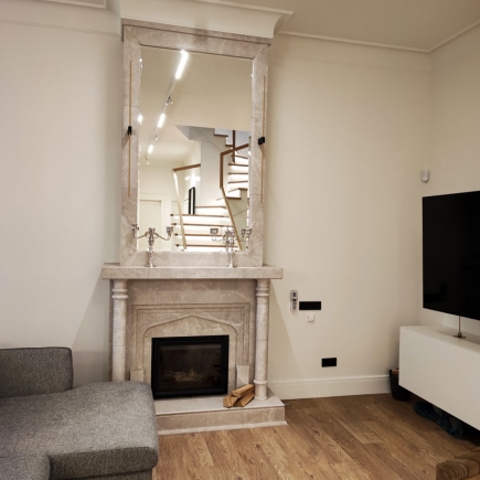 Marble fireplace with tall framed mirror above, reflecting the staircase
