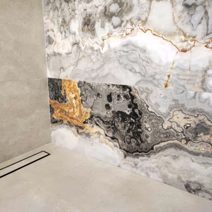Marble tile detail with dramatic gold and black veining beside a curbless shower drain
