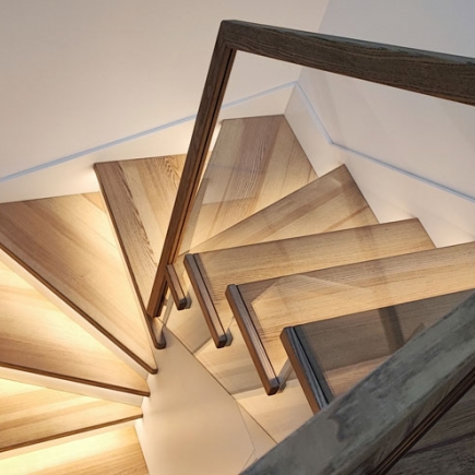 Overhead view of a spiral staircase landing with wood treads and dark handrail