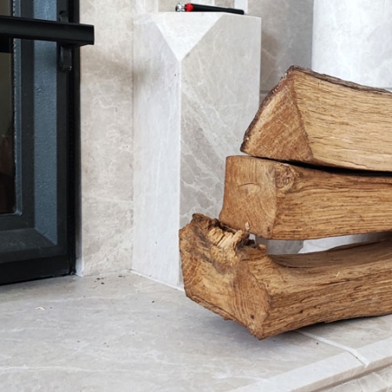 Stacked firewood beside the marble fireplace surround