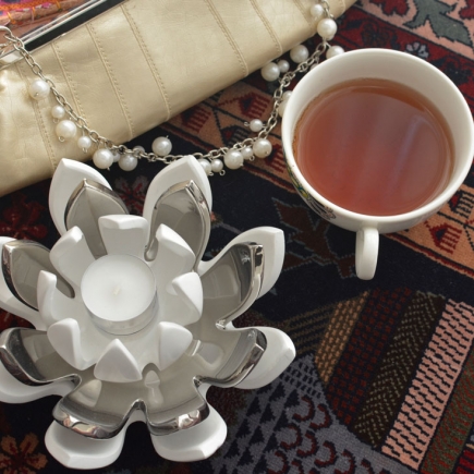 Beaded clutch, pearl necklace, and a cup of tea styled on the patterned rug