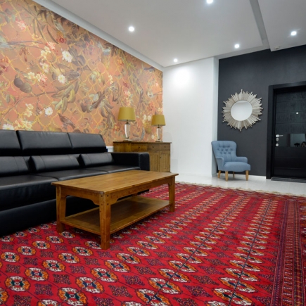 Living room with black leather sofa, wooden coffee table, and bird-and-floral wallpaper feature wall