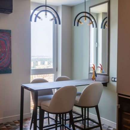 Bar-height breakfast nook beneath arched pendant lights with a city view