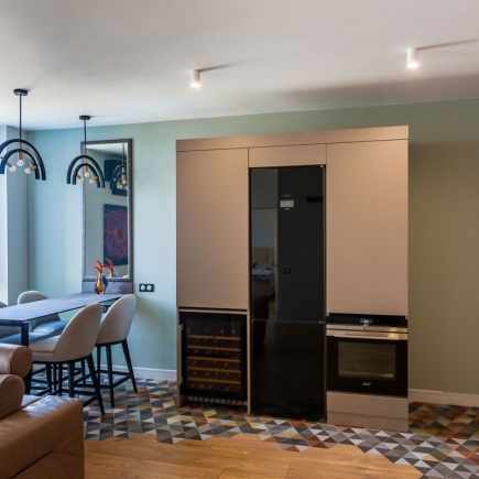 Built-in wine fridge and oven flanked by cabinetry, with the dining area beyond